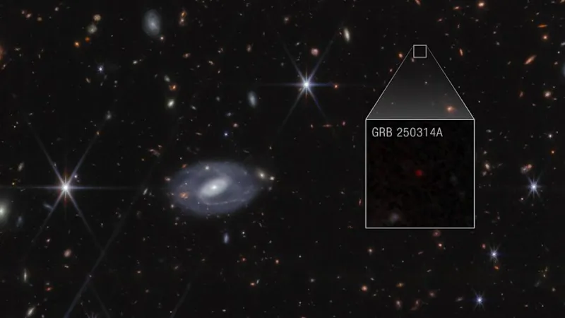 Webb image shows hundreds of galaxies of all shapes and sizes against the black background of space. Toward the center-left is a large white spiral galaxy that is almost face-on. To the right of this is a large box, which zooms in on an area at top right. Within the box is a faint red dot at the center, with the label GRB 250314A.