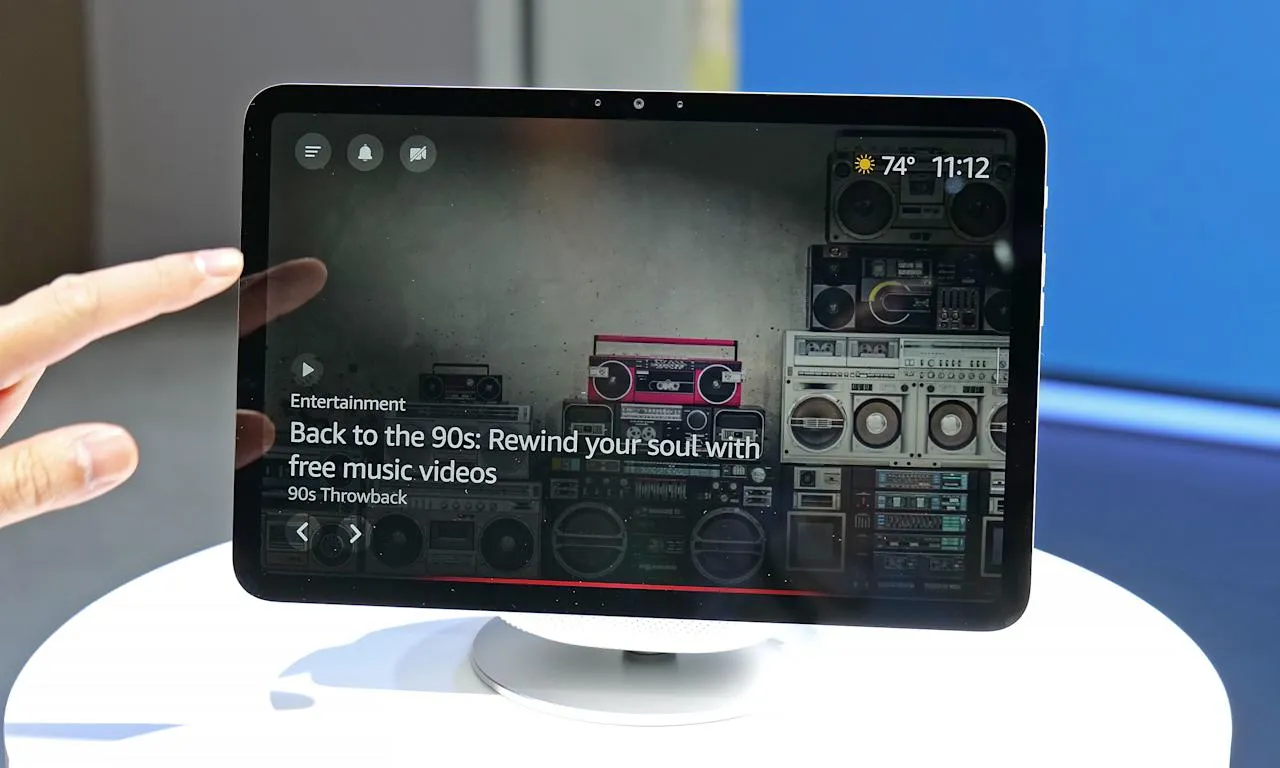 Рука держит пульт Amazon Basics Smart Remote, направленный на колонку Echo на столе