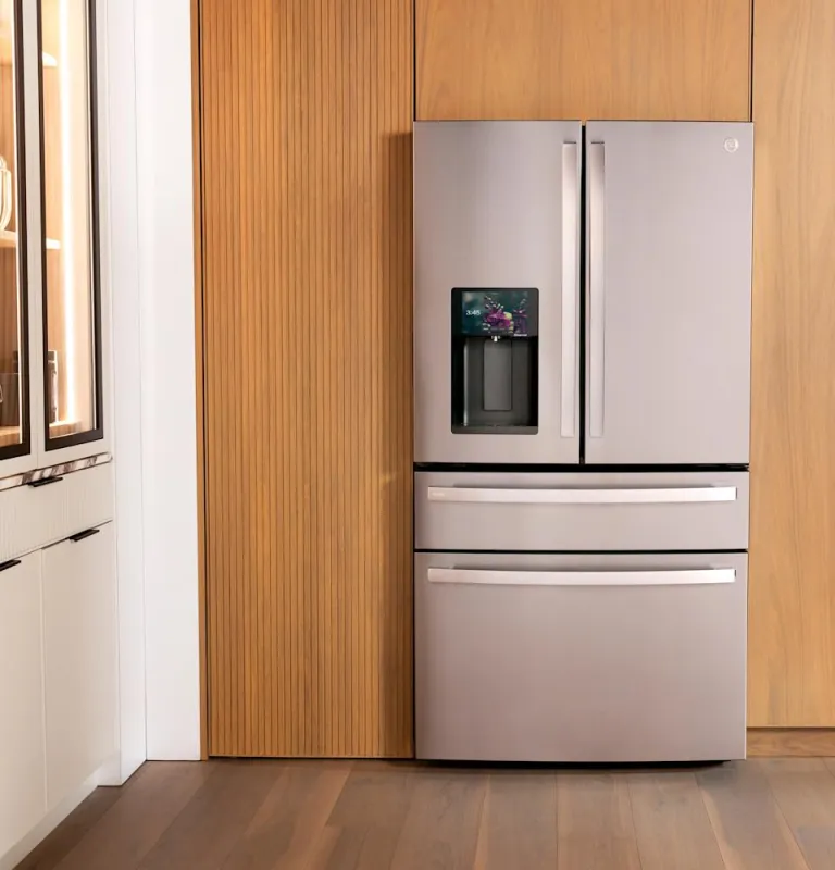 A silver four door refrigerator nestled in wooden shelves.