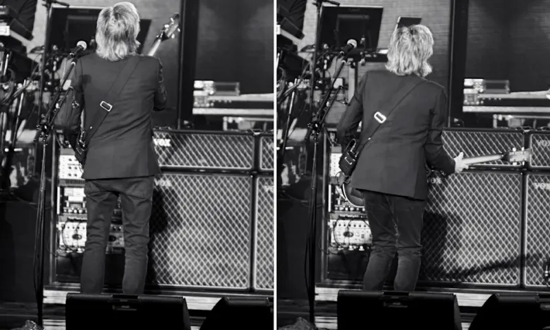 Пол Маккартни играет на бас-гитаре вживую. Он бросает взгляд в сторону с полусомкнутыми губами.